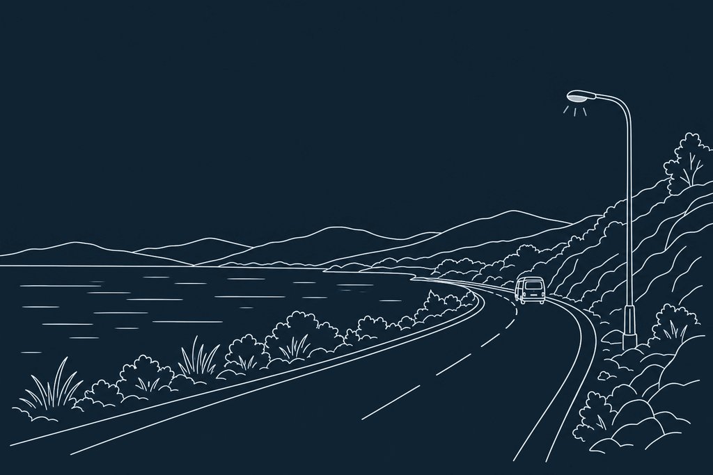 Line drawing of a two-lane road curving along a big lake shore toward distant hills, with a small tour van far down the road
